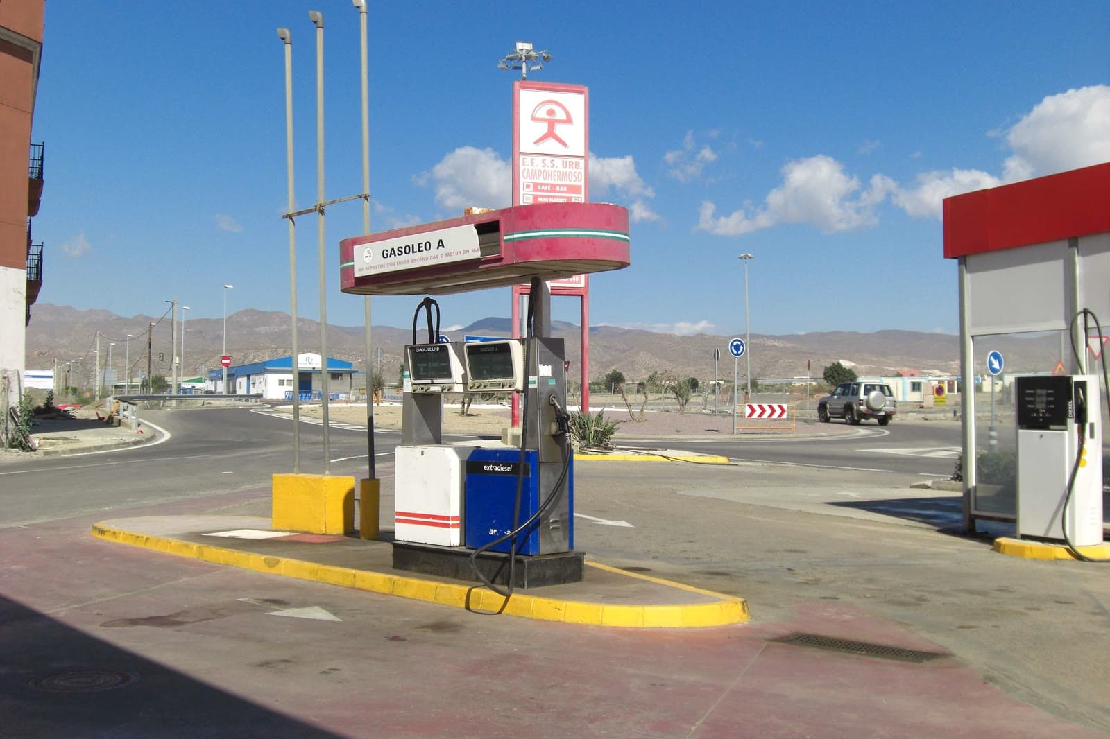 Surtidores de gasóleo bajo una marquesina con el rótulo «Gasóleo A» en una gasolinera junto a una rotonda