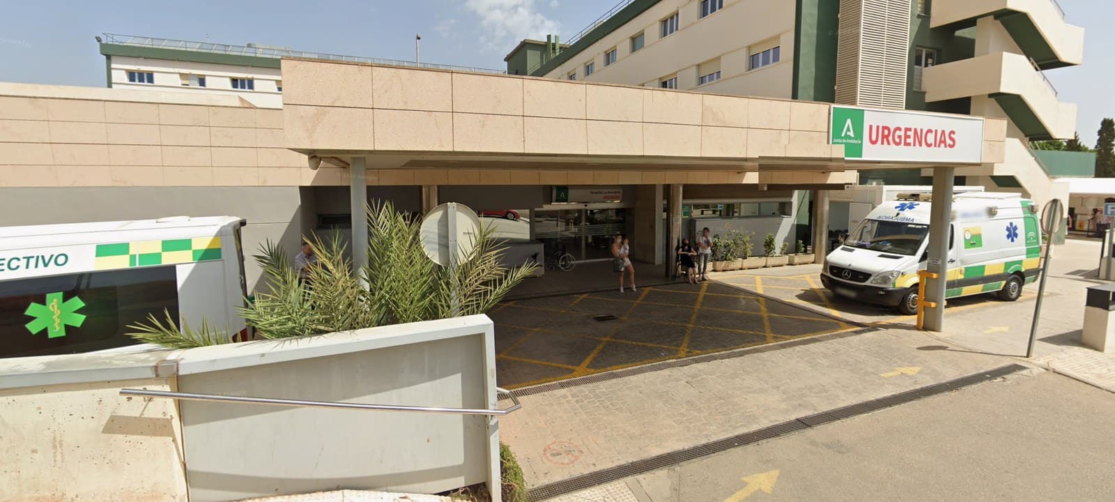 Entrada de Urgencias del Hospital Comarcal de la Axarquía, en Vélez-Málaga, con el rótulo de la Junta de Andalucía y dos ambulancias aparcadas a los lados.