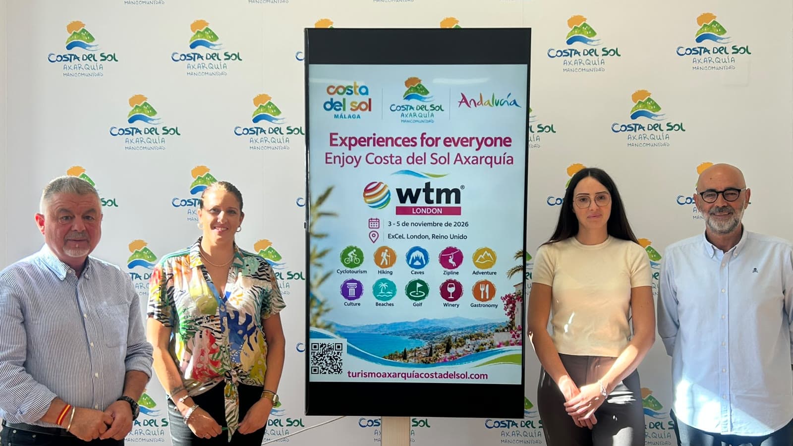 Cuatro personas de pie junto a una pantalla con el cartel de la Axarquía para la WTM de Londres, del 3 al 5 de noviembre de 2026, ante un photocall con el logotipo Costa del Sol Axarquía.