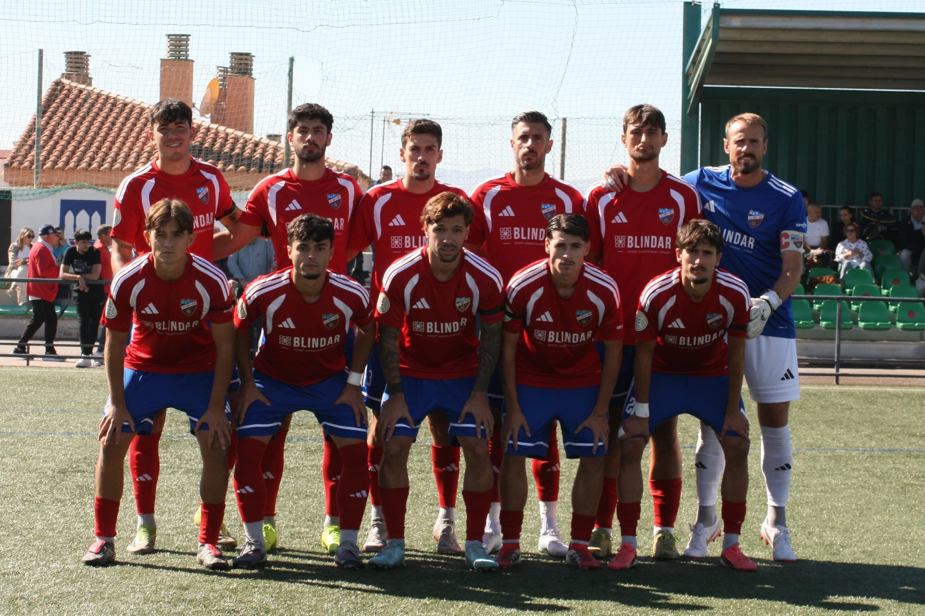 El once inicial del UD Torre del Mar, con camiseta roja y pantalón azul, posa en el campo antes del partido en Huétor Vega.