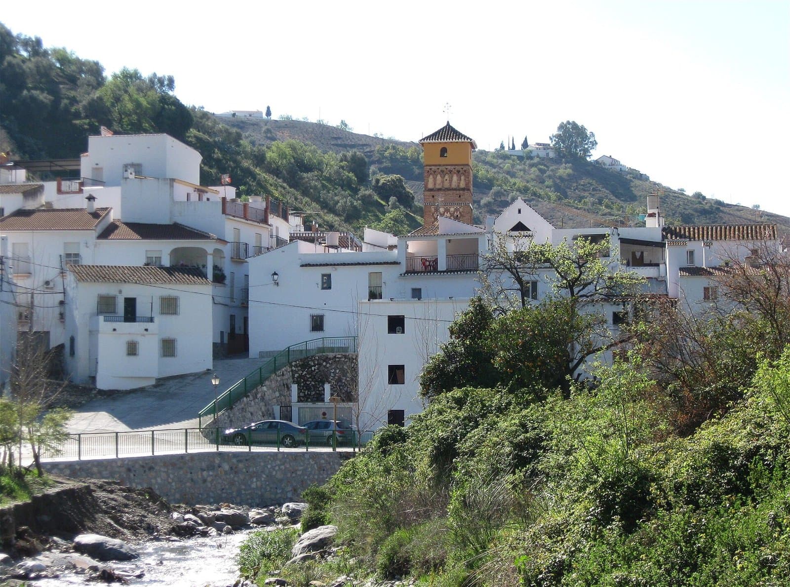 Vista de Árchez, con sus casas blancas y la torre mudéjar de la iglesia sobre el río Turvilla