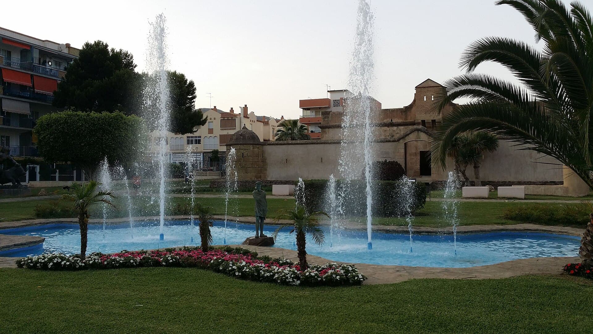 La Casa Fuerte Bezmiliana, en Rincón de la Victoria, con una fuente y jardines con palmeras delante.