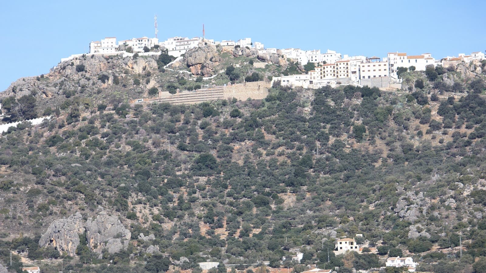 El casco urbano de Comares, de casas blancas, en lo alto de un cerro rocoso cubierto de olivos y monte bajo, visto desde un mirador de la carretera MA-3108.