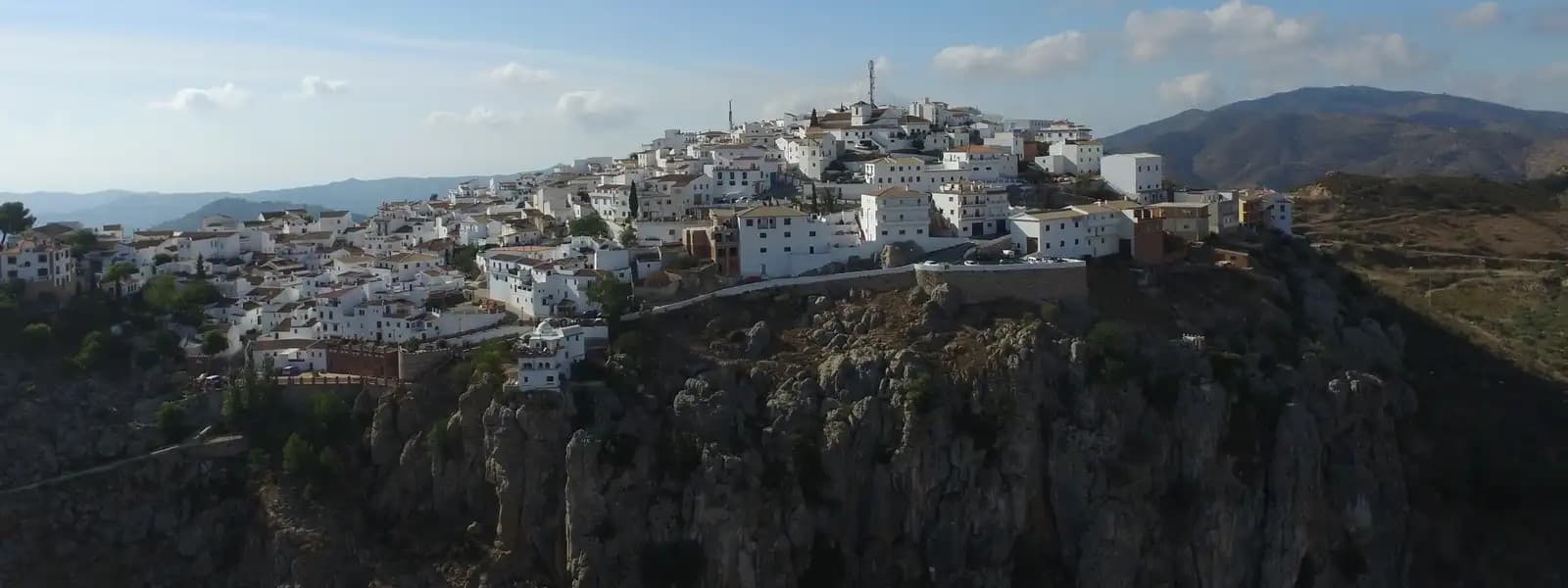 Vista aérea del casco urbano de Comares, con sus casas blancas sobre el peñón y las montañas de la Axarquía al fondo