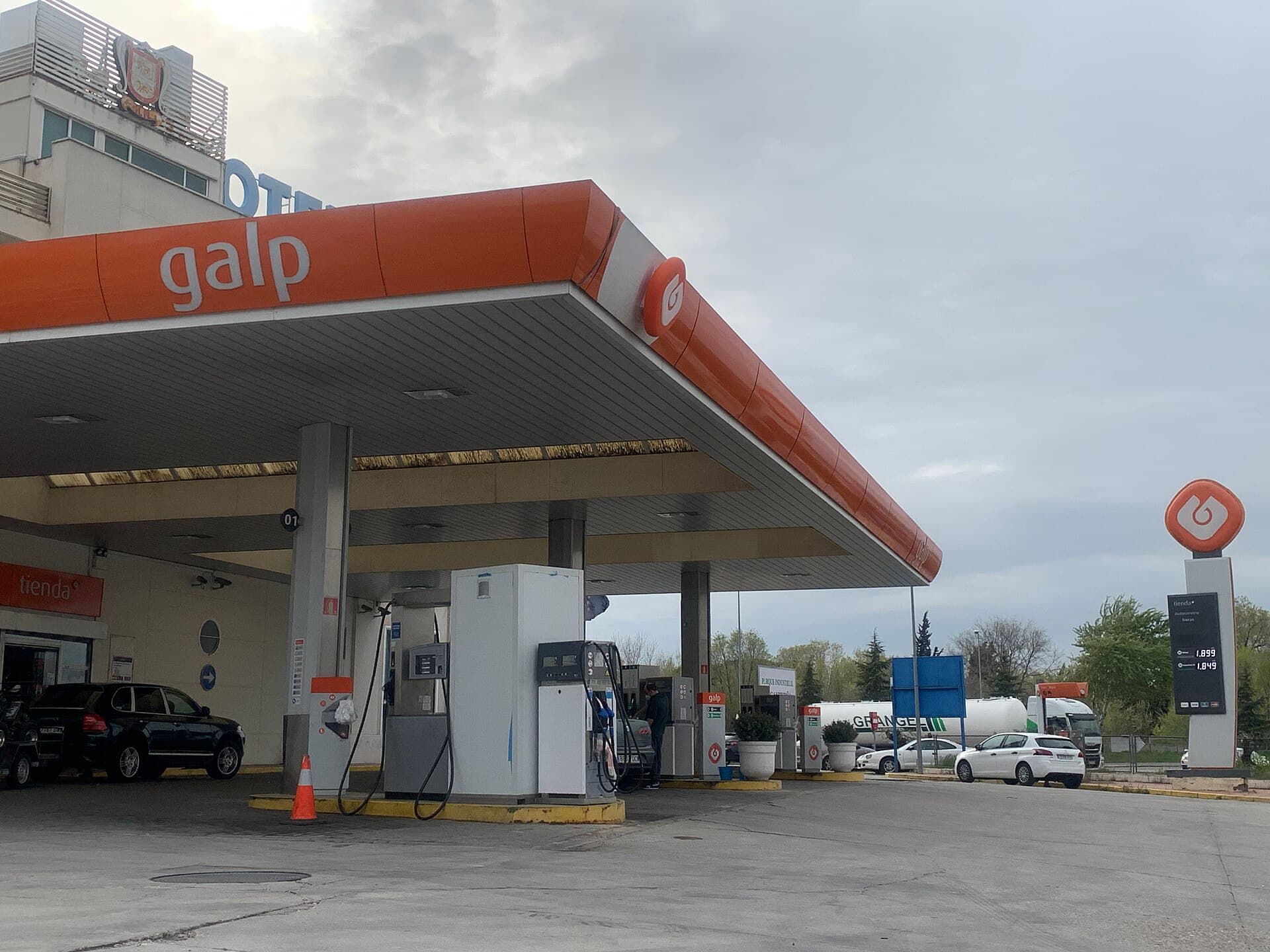 Marquesina de una gasolinera con los surtidores y varios coches repostando.