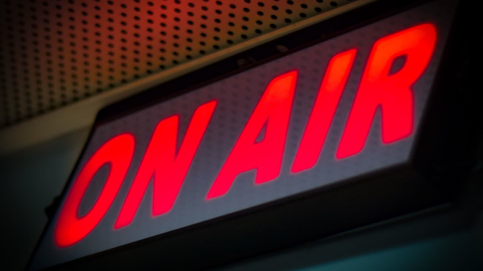 Cartel luminoso rojo con las palabras «On Air» encendido en un estudio de emisión.